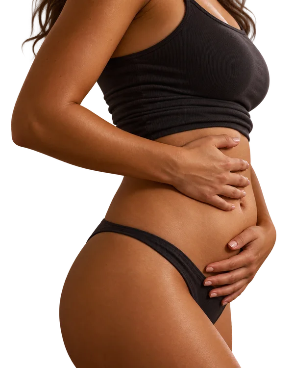 Mulher com as mãos na barriga, expressando desconforto com o inchaço